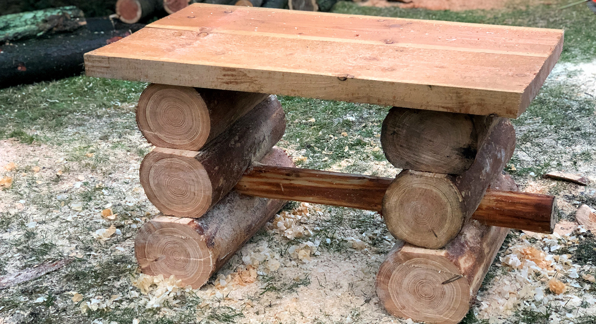 Uma mesa de bricolage para espaços verdes em madeira já acabada, num relvado, rodeada de serradura