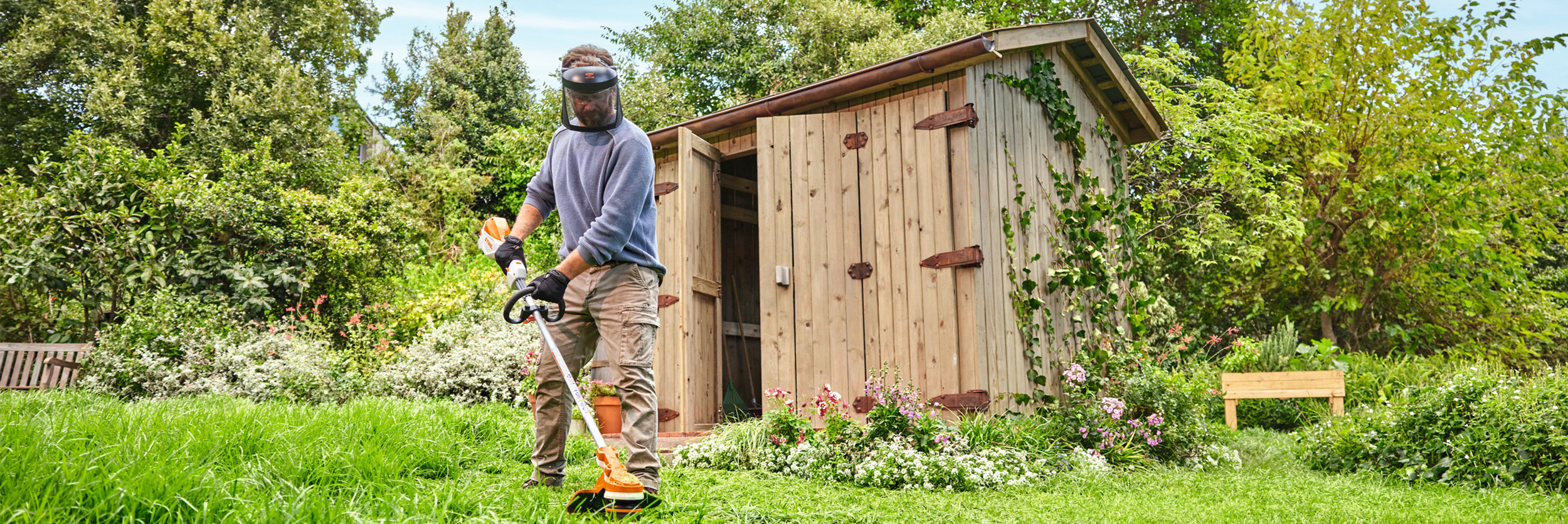  Um homem apara a relva com a motorroçadora a bateria STIHL FSA 70 R