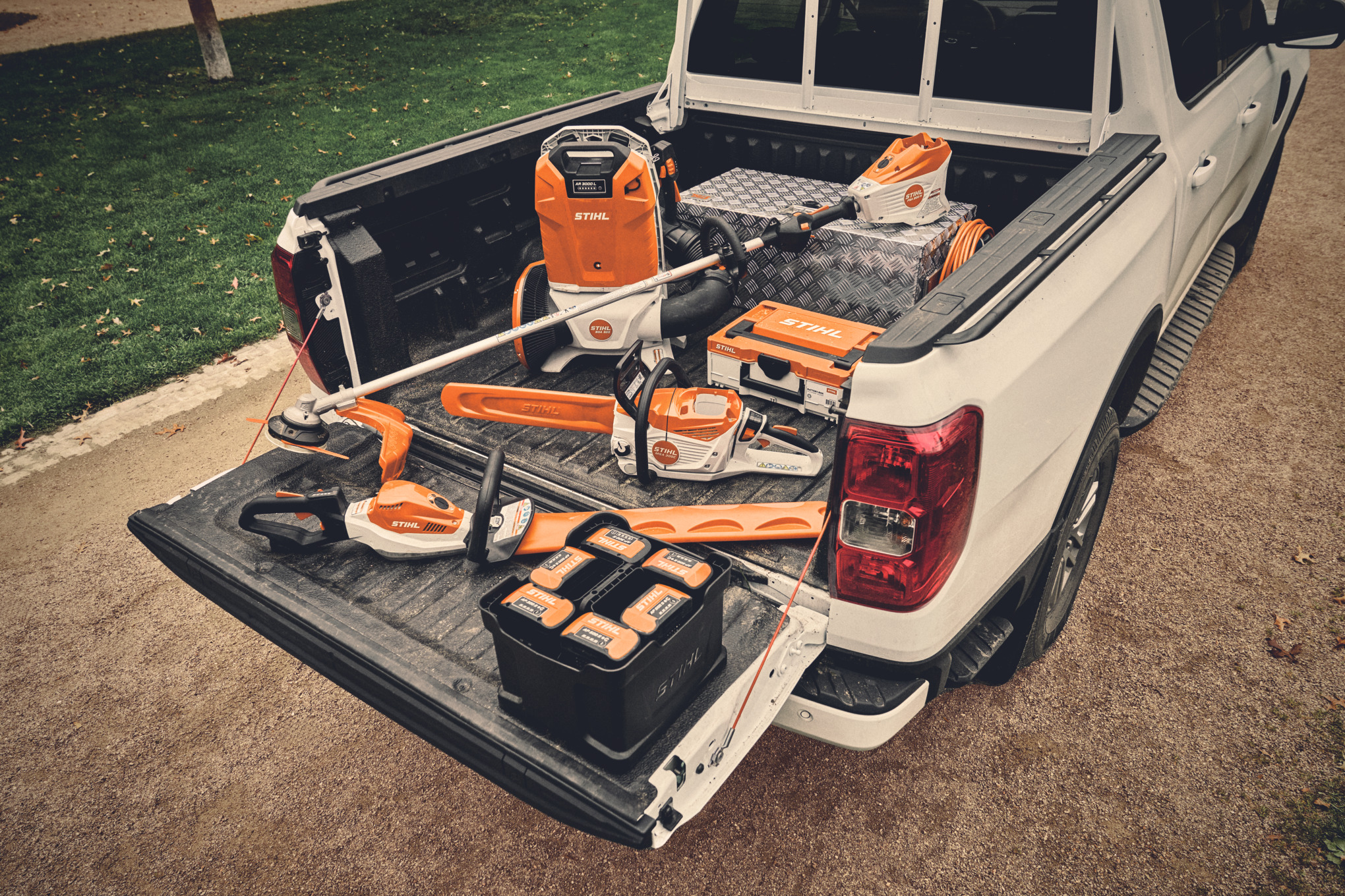Várias ferramentas a bateria do sistema STIHL AP e as respectivas baterias na área de carga de um veículo.