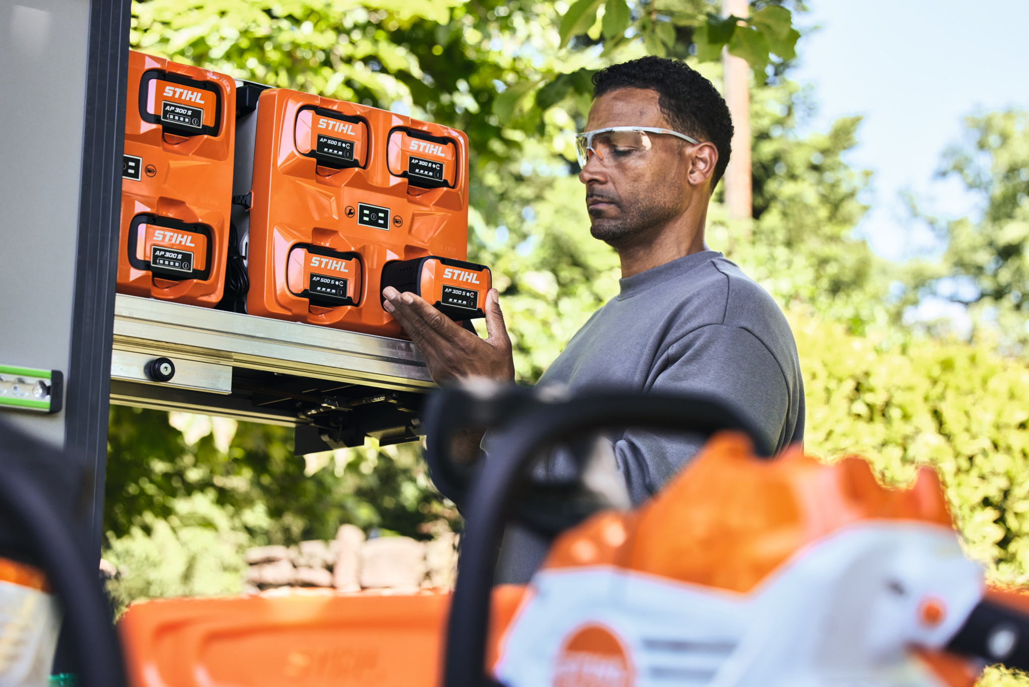 Um homem com óculos de protecção retira uma bateria STIHL AP 300 S do fundo do depósito.