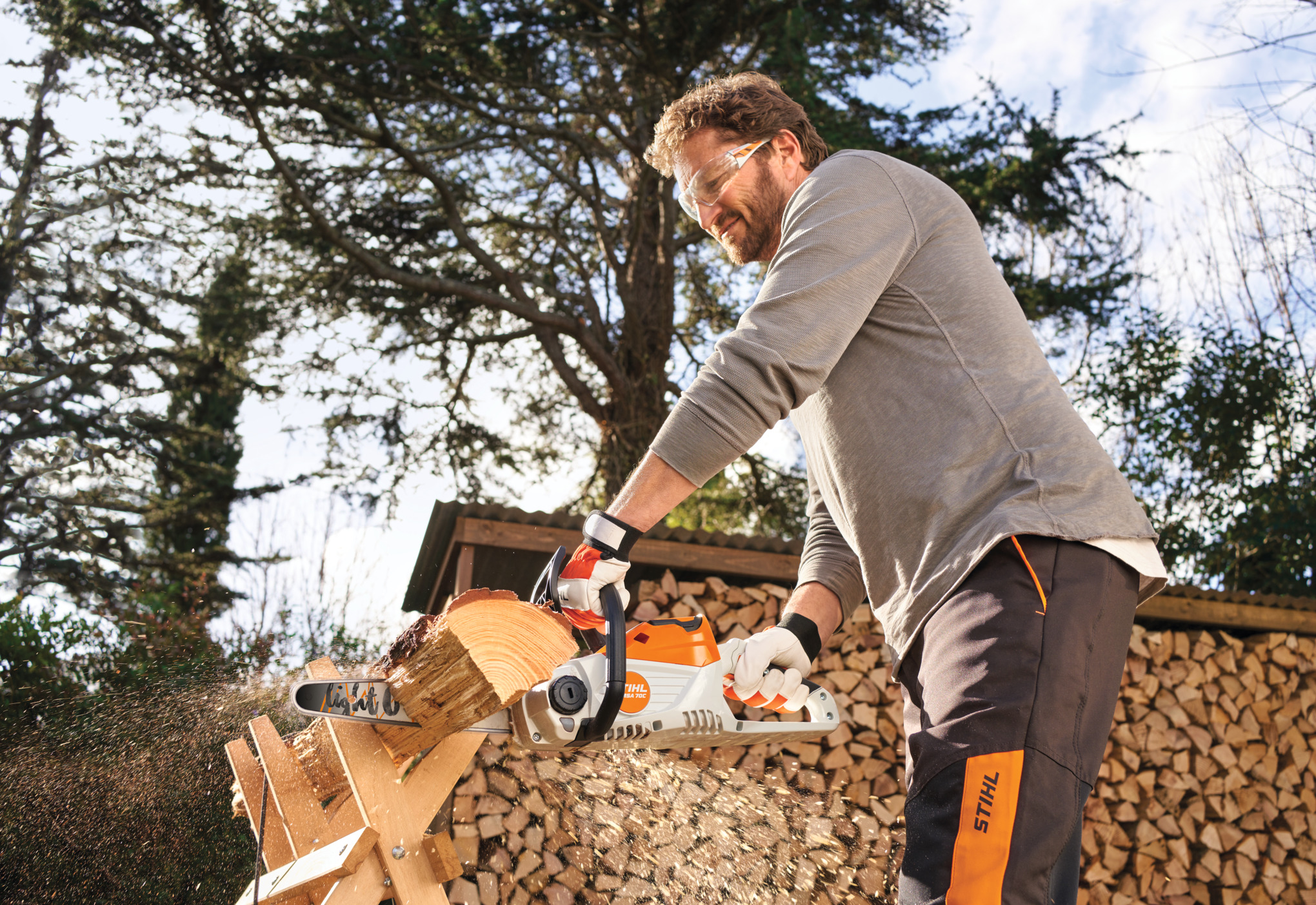 Um homem a serrar madeira num cavalete com uma motosserra STIHL