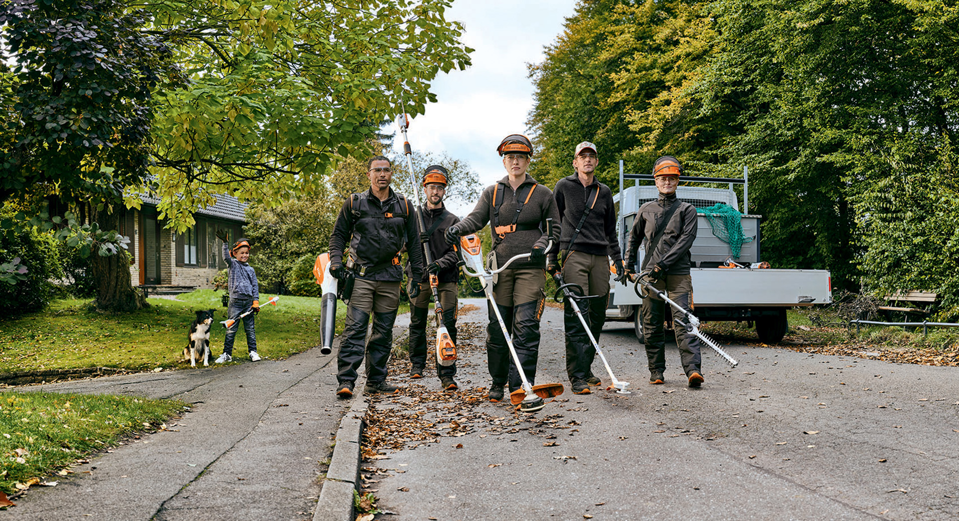 Uma equipa de jardinagem e paisagismo com máquinas a bateria profissionais da STIHL a descer uma rua.