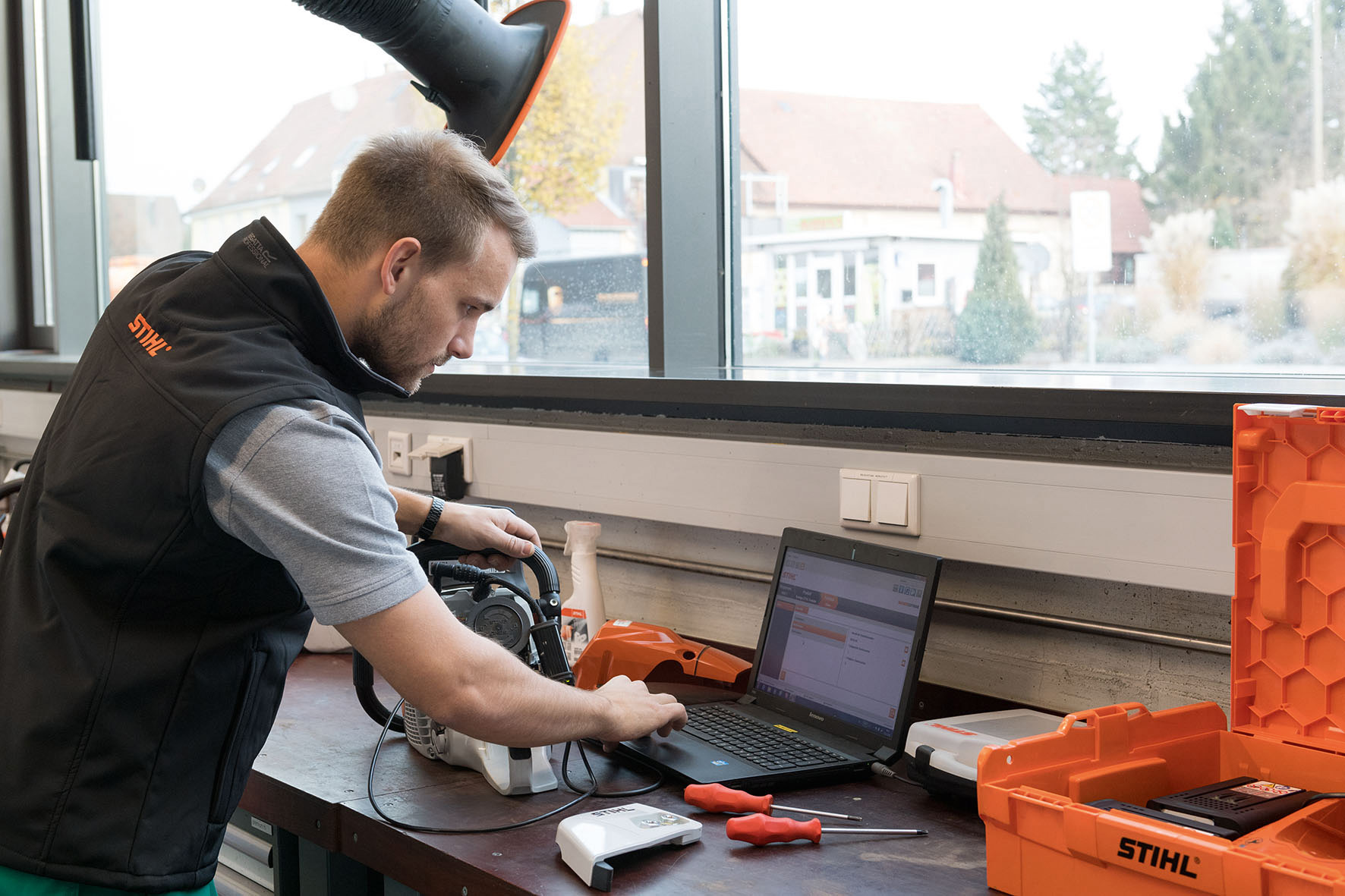 Homem a olhar para um computador portátil com uma motosserra STIHL ao seu lado – soluções digitais STIHL