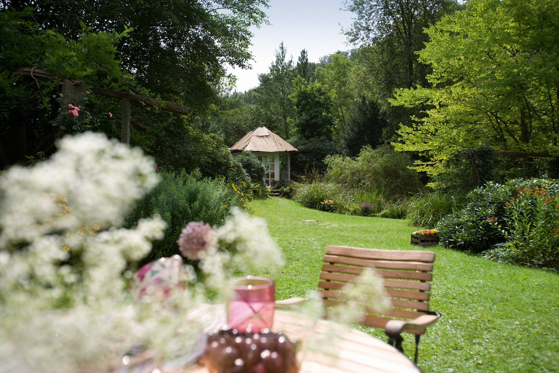 Manutenção de jardins correta num relvado verde, uma cadeira em primeiro plano e uma sala de jardim à distância