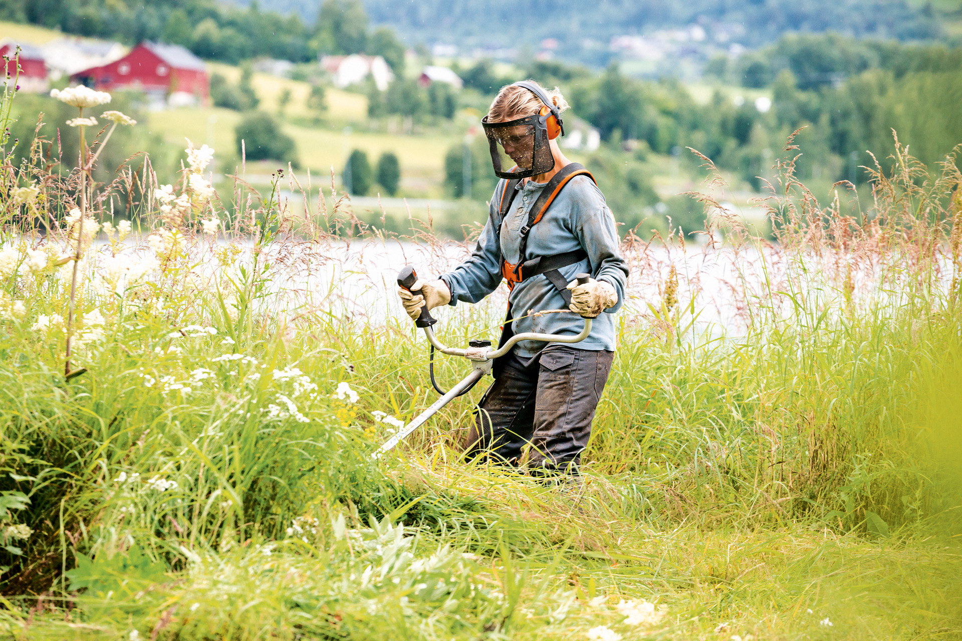 Um homem a usar vestuário de proteção a trabalhar em erva comprida com uma motorroçadora a gasolina STIHL FS 240