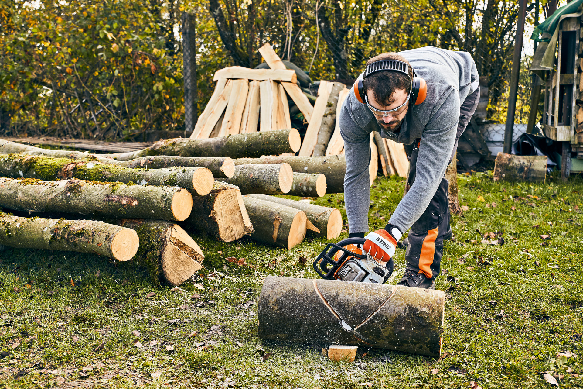 Um homem com uma STIHL MS 180 a fazer o seu próprio banco de bricolage para espaços verdes com uma motosserra 