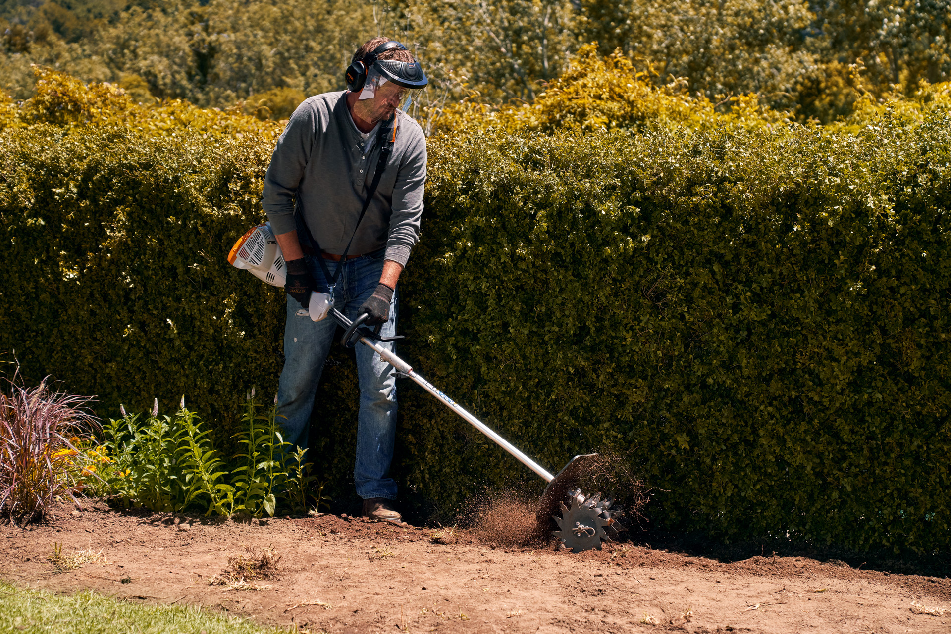 Um homem de viseira e luvas com um STIHL KombiEngine KM 56 RC-E – cuidar do jardim no inverno