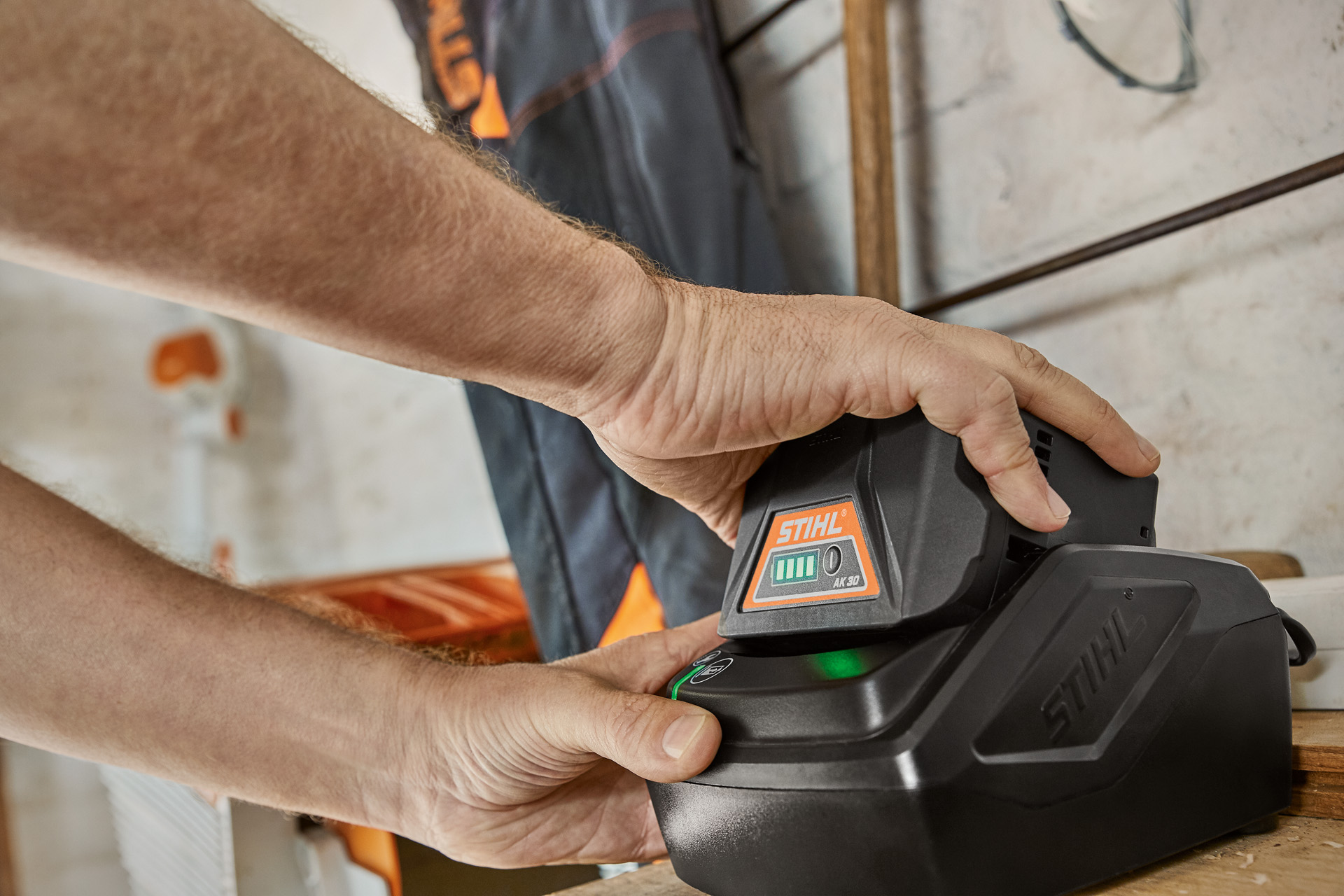 Um homem a carregar uma bateria STIHL numa estação de carga.