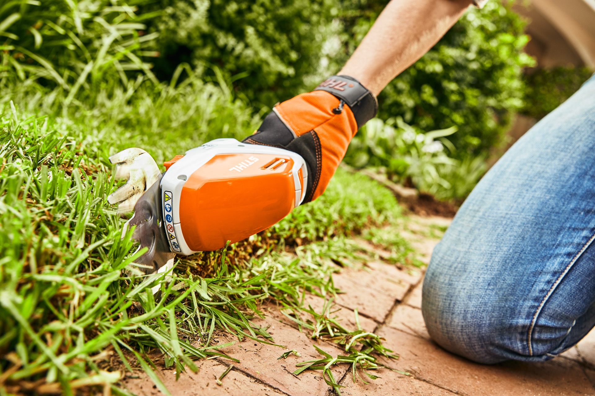 Minipodadora a bateria STIHL HSA 26 a ser usada para aparar os rebordos de um relvado