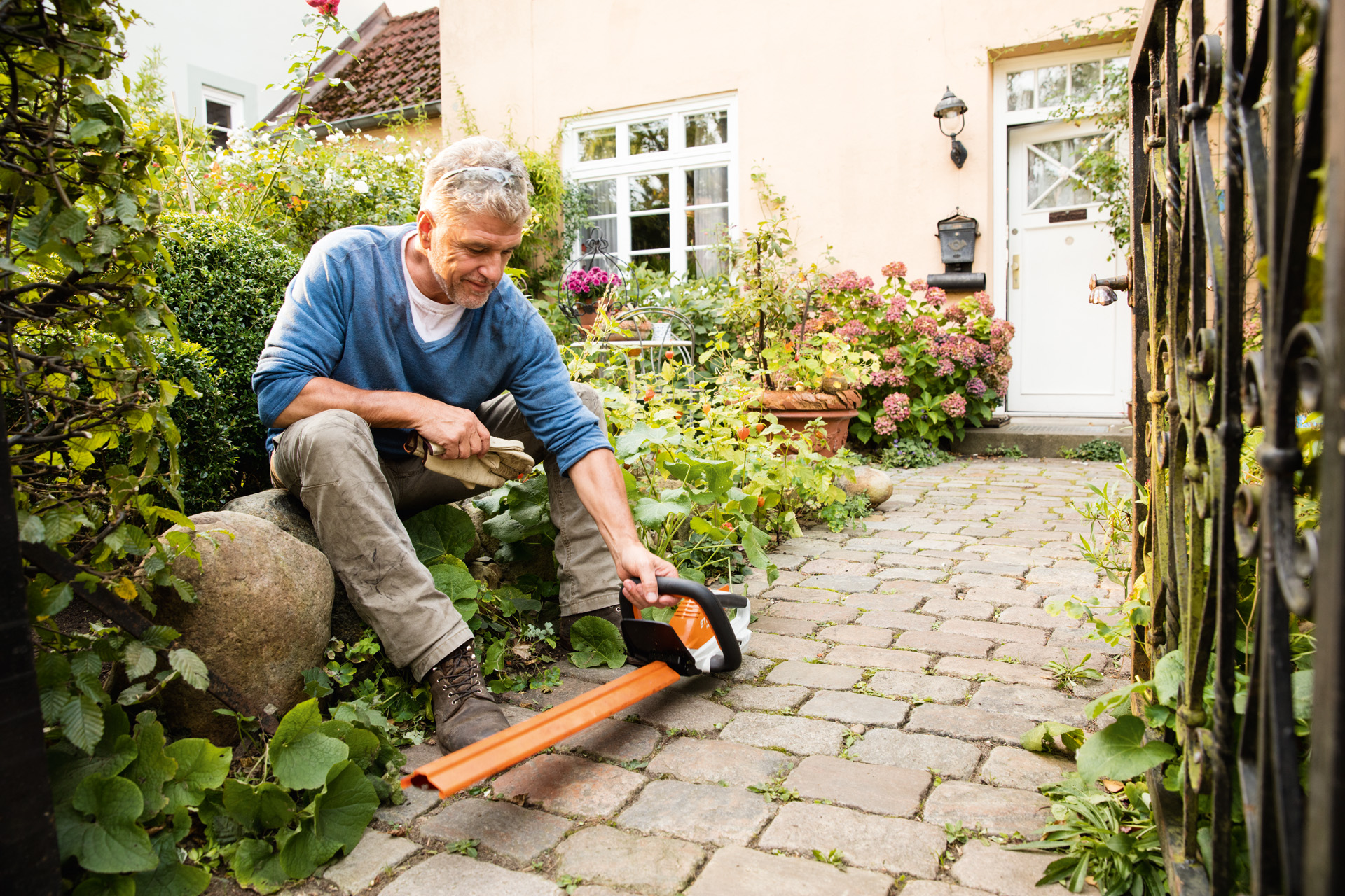 Um homem com uma podadora de sebes a bateria HSA 45 da série STIHL AI