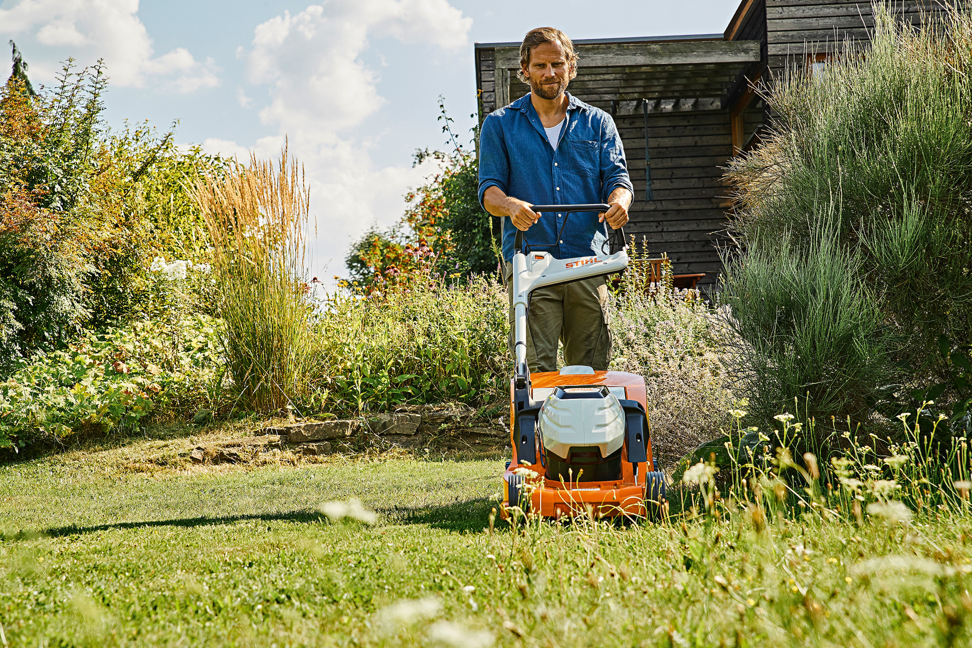 Um homem aplica as dicas dos cuidados com a relva no verão com um corta-relva a bateria STIHL RMA 448 P-C