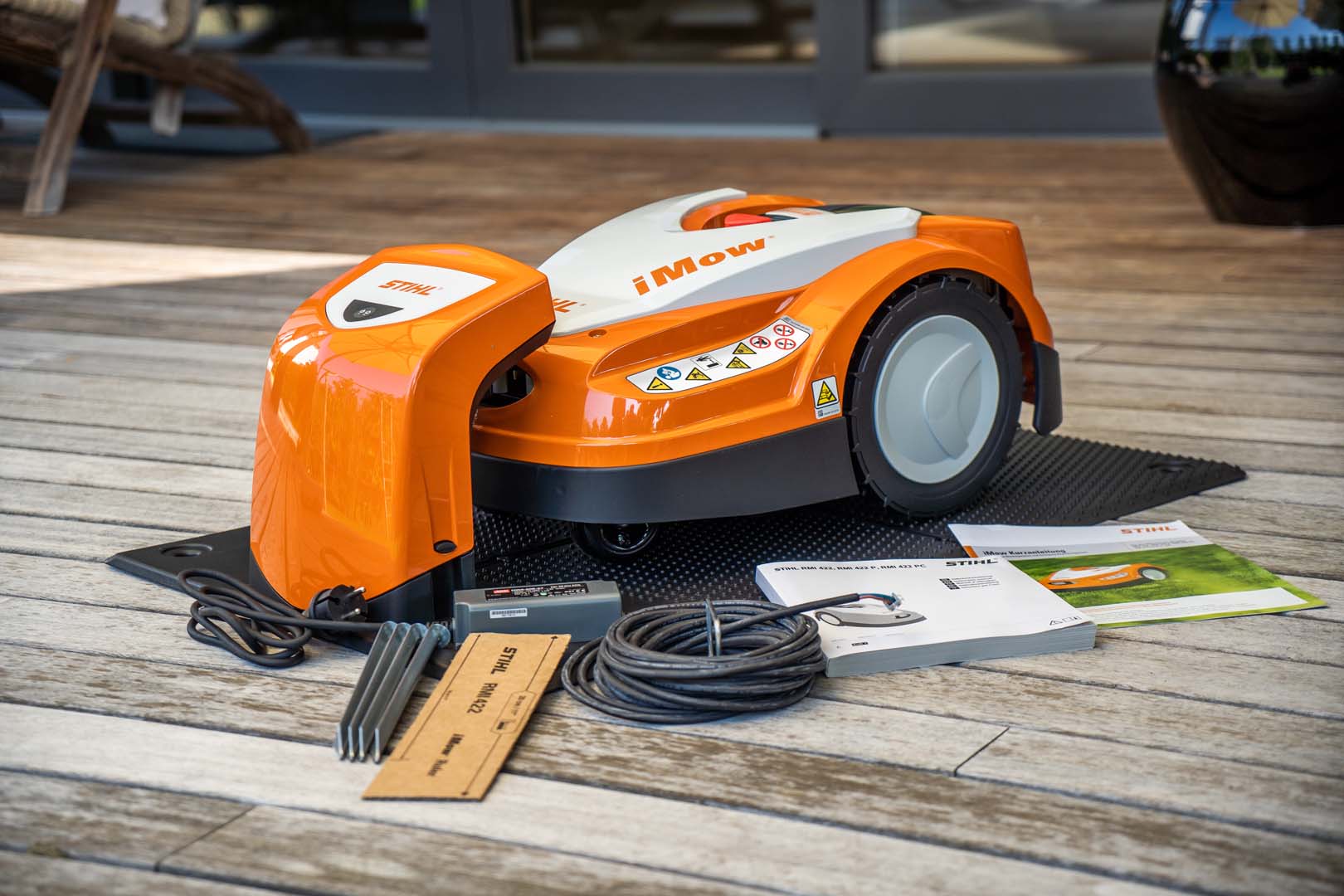 Um robot corta-relva STIHL iMOW® 422 no deck com cabo e instruções de operação