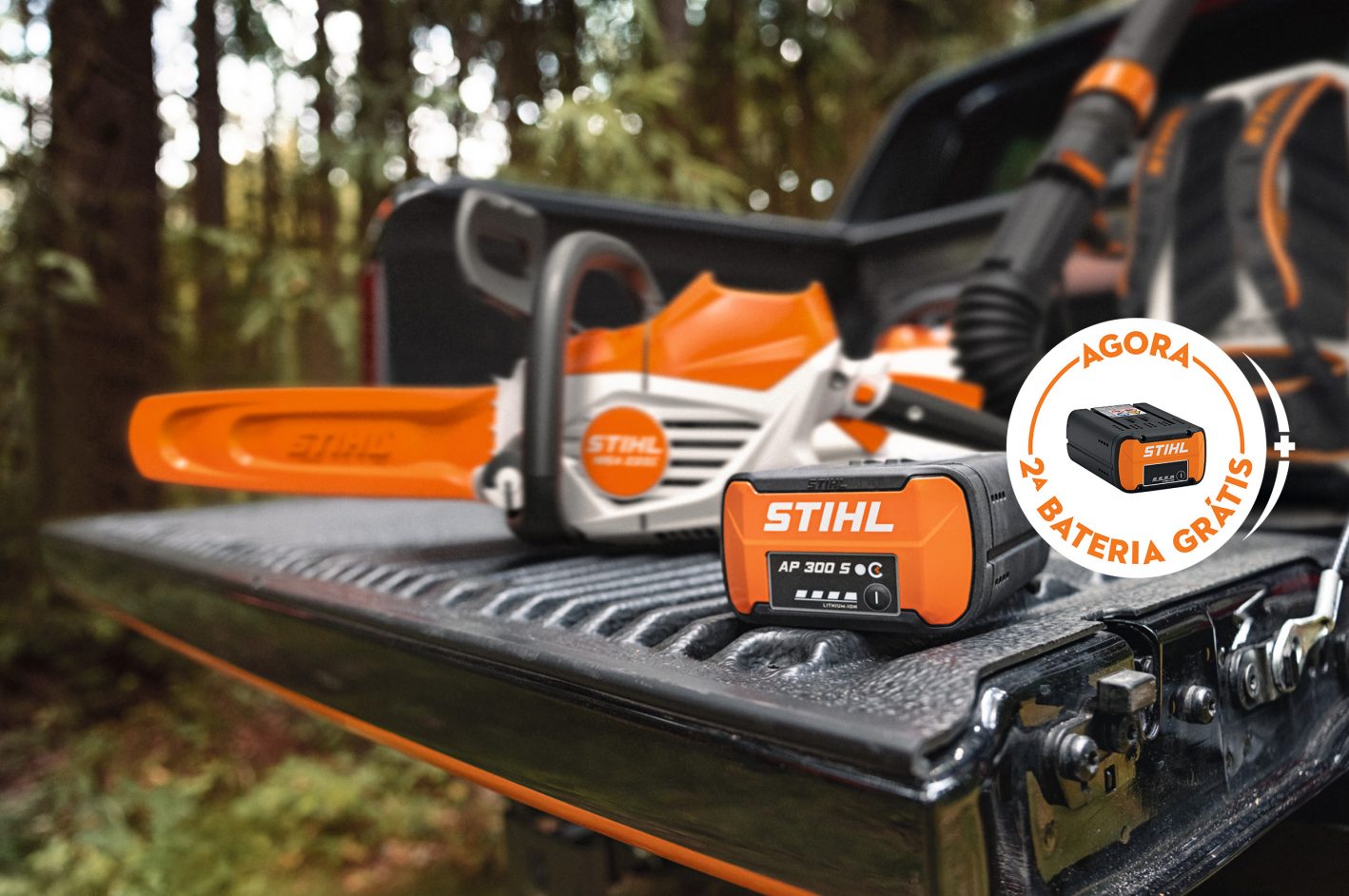 Bateria STIHL AP 500 S na superfície de carga de uma pick-up, juntamente com a nova motosserra a bateria STIHL MSA 300, um destaque publicitário adicional com bateria STIHL e a inscrição "Get a free battery".