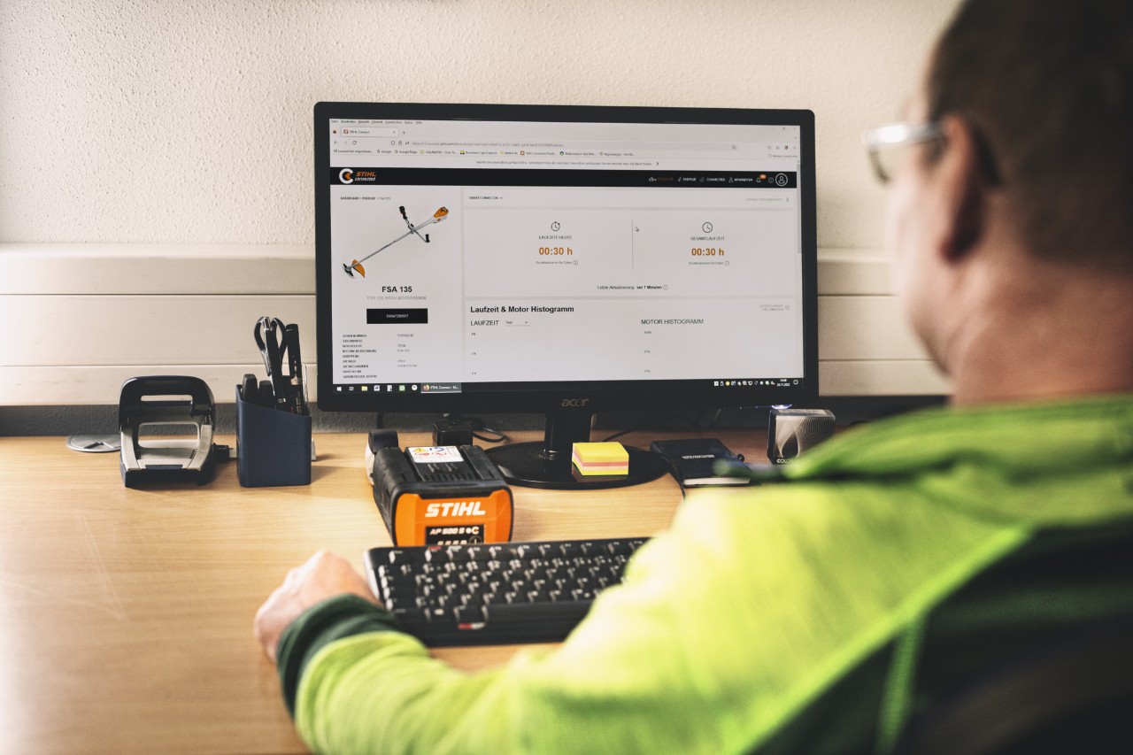 Um homem senta-se em frente ao seu computador e trabalha com o portal STIHL connected