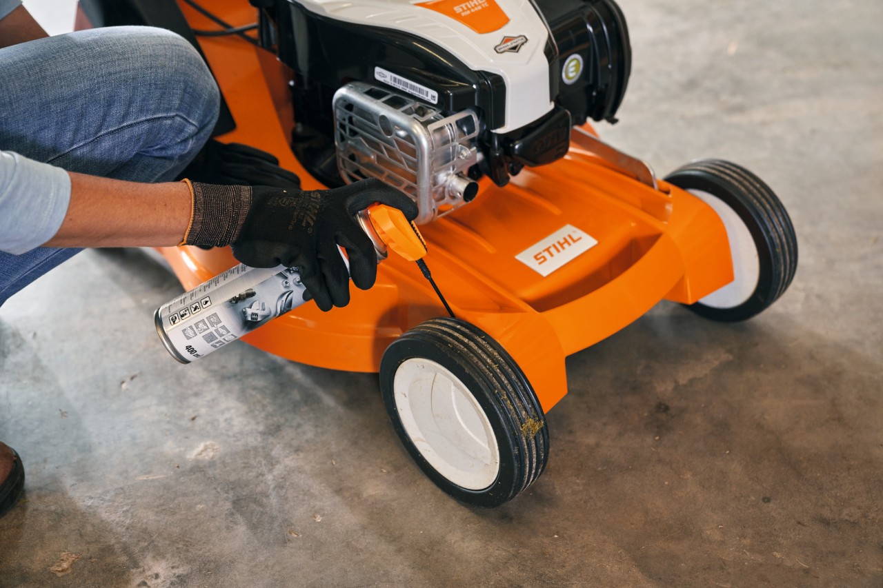 Uma mulher armazena o seu corta-relvas a gasolina STIHL RM 448 TC numa garagem